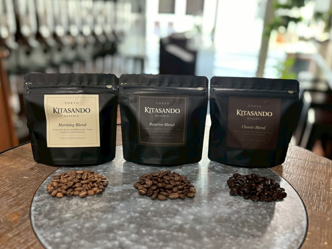 Kitasando Reserveのコーヒー豆パウチ3種（Morning Blend・Reserve Blend・Classic Blend）と、それぞれの焙煎豆が円形の台に並ぶ様子。